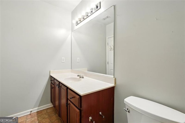 half bathroom with toilet, baseboards, and vanity