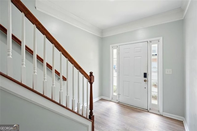 foyer entrance featuring crown molding, stairs, baseboards, and wood finished floors