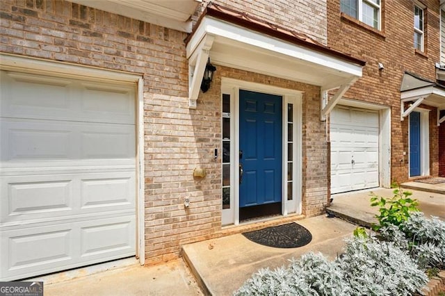 entrance to property featuring brick siding and a garage