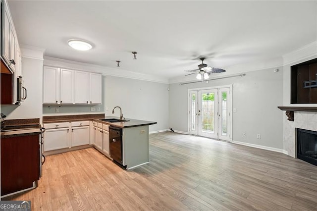 kitchen with a peninsula, a ceiling fan, a sink, dark countertops, and open floor plan