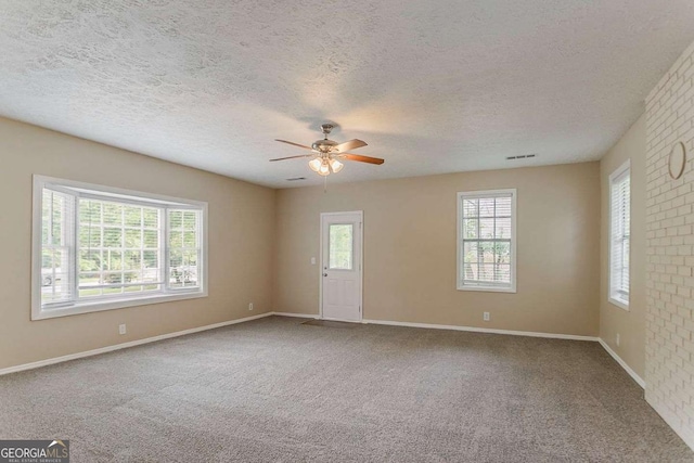 spare room featuring a textured ceiling, carpet flooring, baseboards, and a ceiling fan