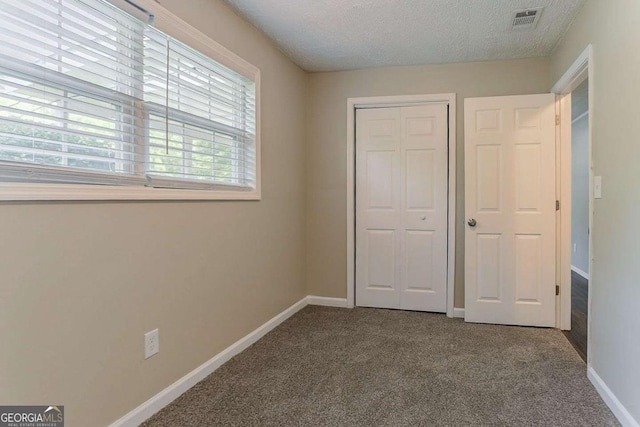 unfurnished bedroom with a closet, visible vents, baseboards, and carpet floors