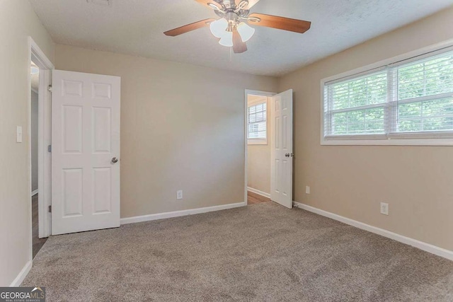 spare room with carpet, baseboards, and ceiling fan