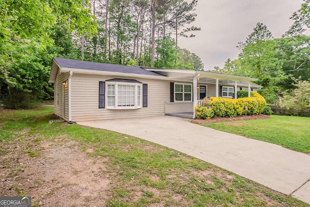 ranch-style home featuring covered porch, driveway, and a front lawn