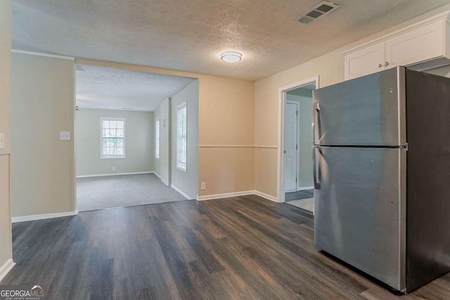 kitchen featuring freestanding refrigerator, a textured ceiling, visible vents, dark wood-style floors, and white cabinets