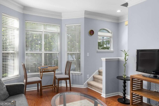 living area with wood finished floors, baseboards, crown molding, and stairs