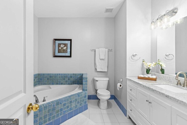 bathroom with toilet, tile patterned floors, vanity, a bath, and baseboards