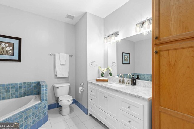 bathroom with toilet, tile patterned floors, tiled tub, and vanity