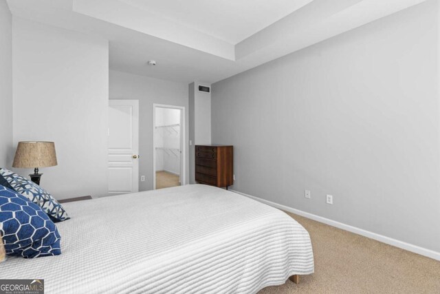 carpeted bedroom featuring baseboards and a raised ceiling