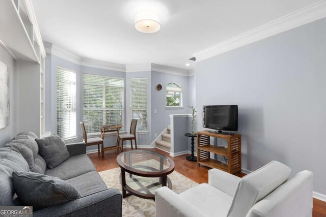 living room with plenty of natural light, crown molding, baseboards, and wood finished floors