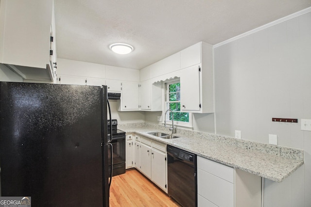 kitchen featuring a sink, white cabinetry, light wood-type flooring, black appliances, and light stone counters