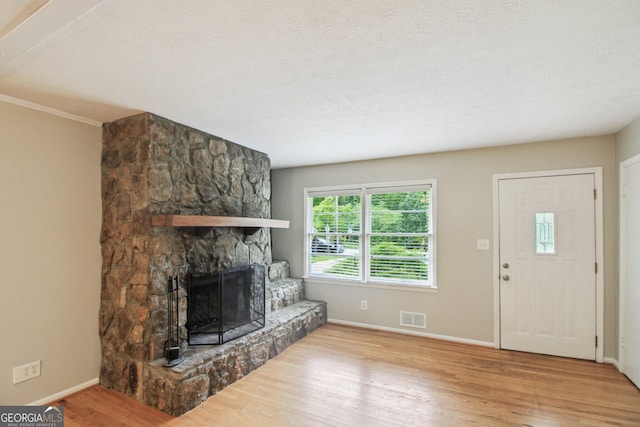 unfurnished living room with a fireplace, baseboards, visible vents, and wood finished floors