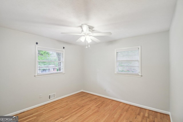 spare room featuring light wood-type flooring, visible vents, baseboards, and ceiling fan