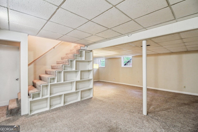 below grade area featuring a paneled ceiling, stairs, carpet, and baseboards