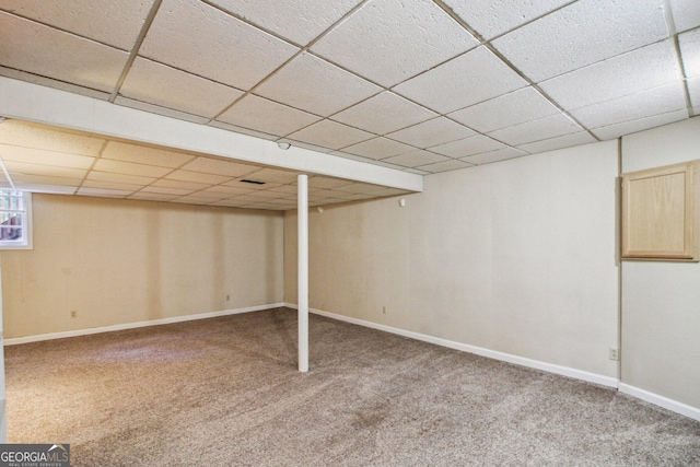 finished basement featuring carpet floors, baseboards, and a drop ceiling