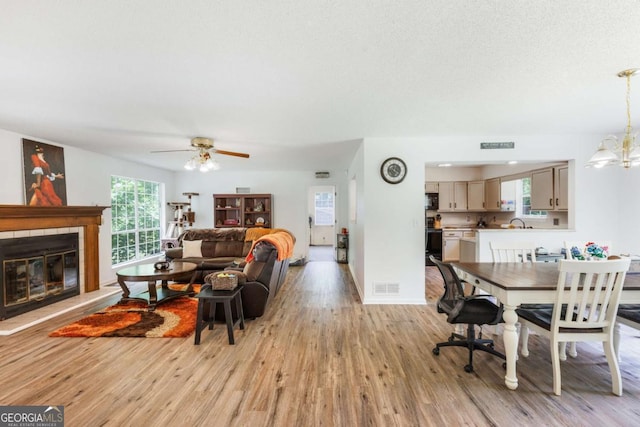 40 Carole Dr, Carrollton, GA 30117 - living room with a tile fireplace, light wood-type flooring, visible vents, baseboards, and ceiling fan