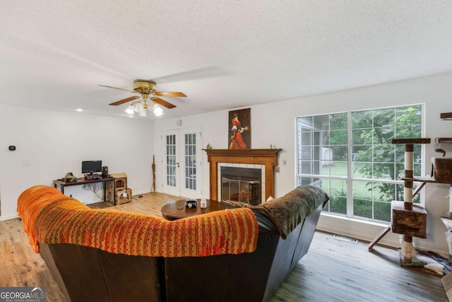 40 Carole Dr, Carrollton, GA 30117 - living area featuring french doors, a textured ceiling, light wood-style flooring, a ceiling fan, and a tile fireplace