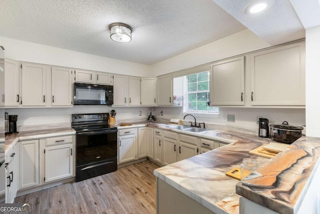 40 Carole Dr, Carrollton, GA 30117 - kitchen with light wood finished floors, a sink, a textured ceiling, black appliances, and light countertops