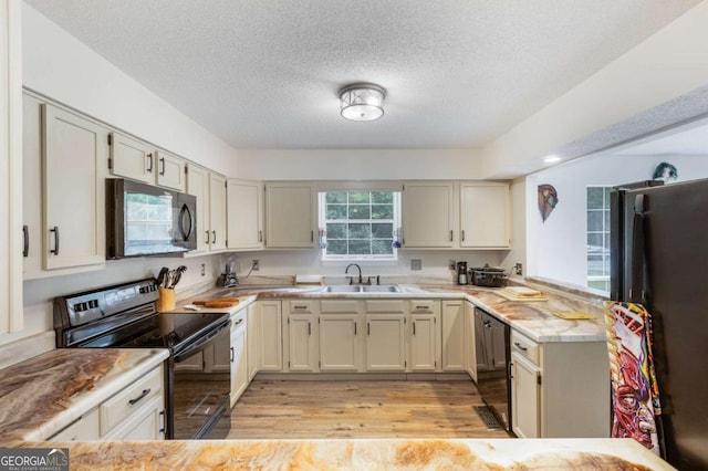 40 Carole Dr, Carrollton, GA 30117 - kitchen featuring a sink, a peninsula, black appliances, light wood-style flooring, and light countertops