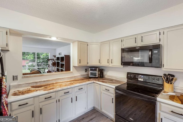 40 Carole Dr, Carrollton, GA 30117 - kitchen with a textured ceiling, light countertops, black appliances, and light wood-style floors