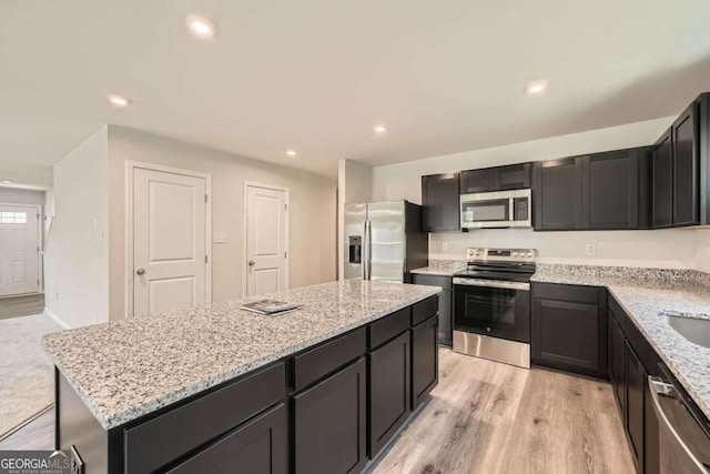 8491 Limerick Ln, Winston, GA 30187 - kitchen with a kitchen island, light wood-style floors, stainless steel appliances, and light stone counters