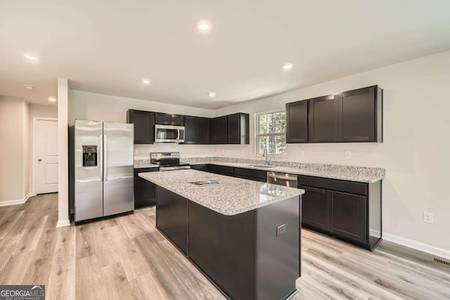 8491 Limerick Ln, Winston, GA 30187 - kitchen with stainless steel appliances, light wood-type flooring, a center island, and light stone countertops