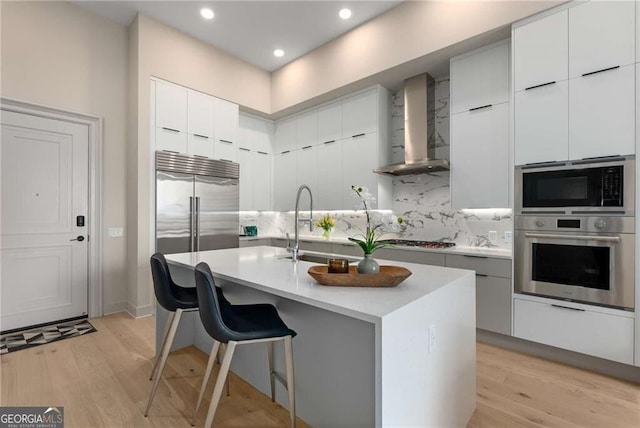 40 12th St NE Unit 803, Atlanta, GA 30309 - kitchen with built in appliances, modern cabinets, wall chimney exhaust hood, light countertops, and tasteful backsplash