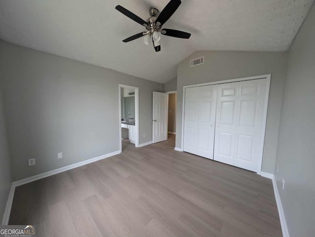 unfurnished bedroom with wood finished floors, baseboards, a closet, vaulted ceiling, and ceiling fan