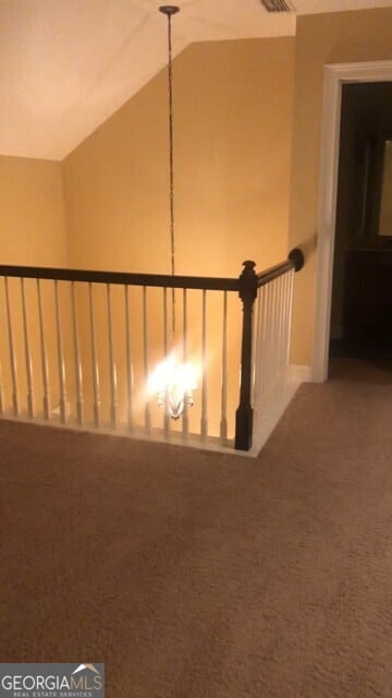hallway featuring vaulted ceiling, carpet flooring, and visible vents