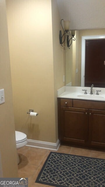 bathroom featuring vanity, toilet, baseboards, and tile patterned floors