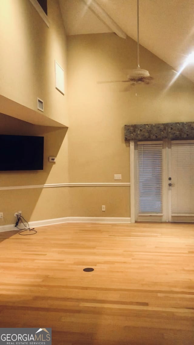 interior space with beam ceiling, wood finished floors, baseboards, and high vaulted ceiling