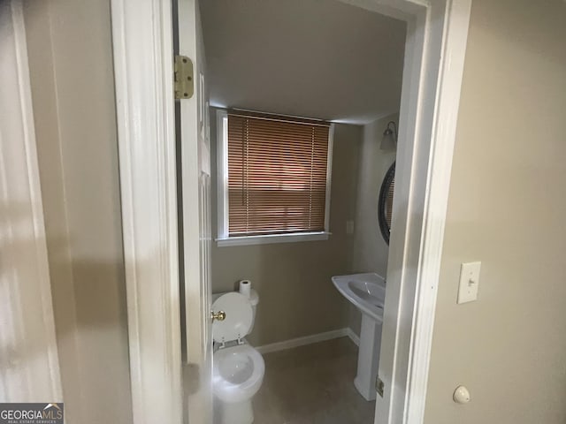 bathroom featuring concrete flooring, toilet, and baseboards