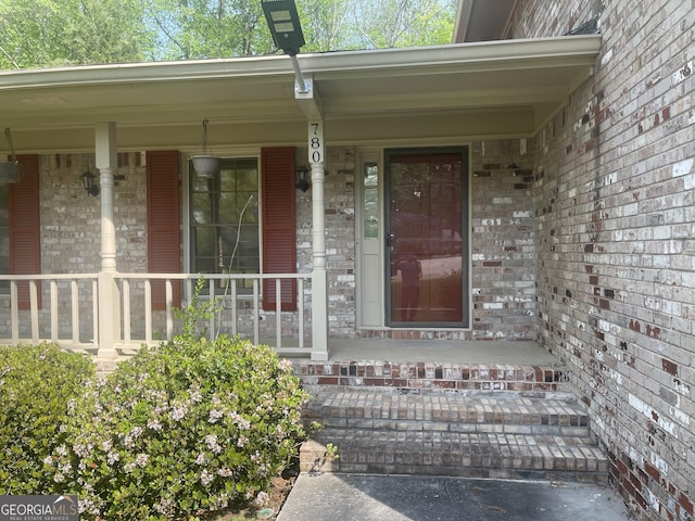property entrance featuring a porch and brick siding