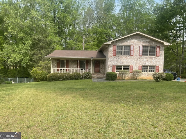 tri-level home featuring covered porch, brick siding, and view of wooded area