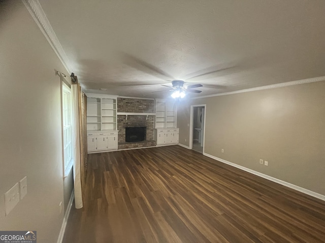 unfurnished living room with ornamental molding, baseboards, a large fireplace, dark wood finished floors, and built in shelves