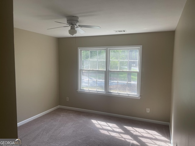carpeted spare room with a ceiling fan and baseboards