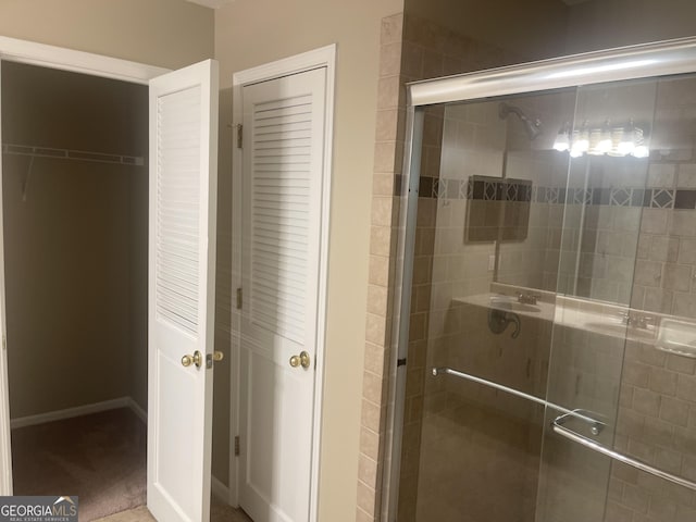 full bath featuring a closet, a shower stall, and baseboards
