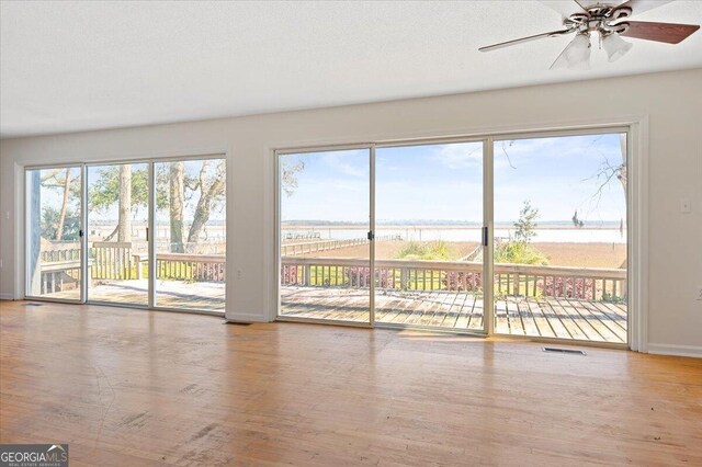 863 Hickory Bluff Rd, Waverly, GA 31565 - unfurnished living room with a water view, baseboards, visible vents, and wood finished floors