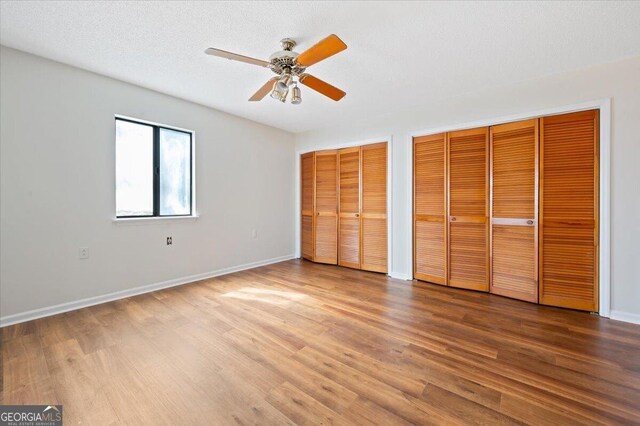 863 Hickory Bluff Rd, Waverly, GA 31565 - unfurnished bedroom featuring two closets, baseboards, a ceiling fan, and wood finished floors