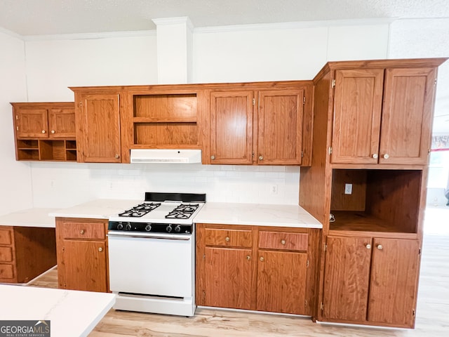 kitchen featuring white gas stove, open shelves, crown molding, backsplash, and under cabinet range hood