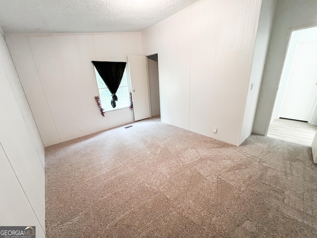 carpeted spare room with a textured ceiling and visible vents