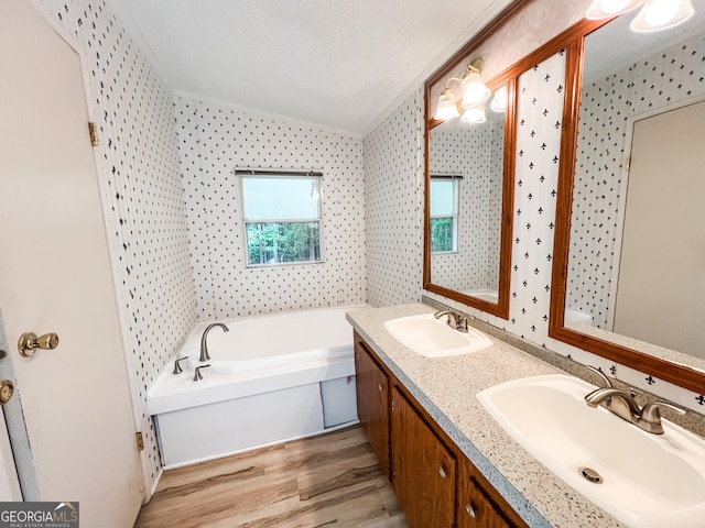 full bath featuring a sink, double vanity, a garden tub, and wood finished floors