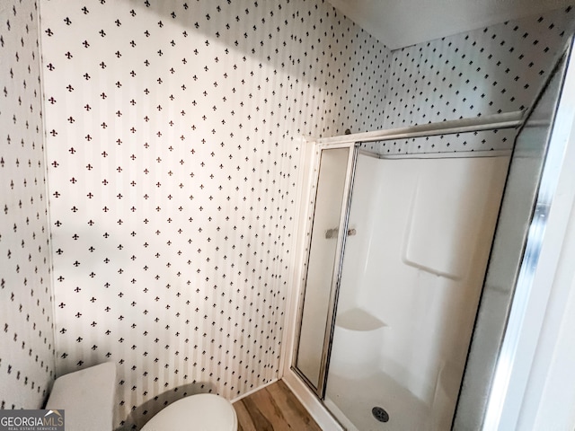full bath with a shower stall, toilet, and wood finished floors