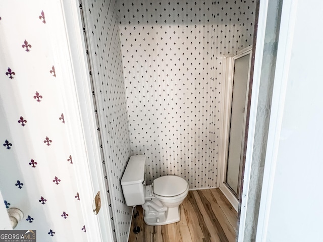 full bathroom with toilet, wood finished floors, and a stall shower