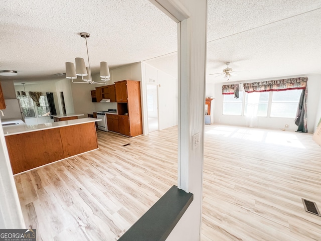 kitchen with brown cabinetry, a textured ceiling, open floor plan, and white gas stove