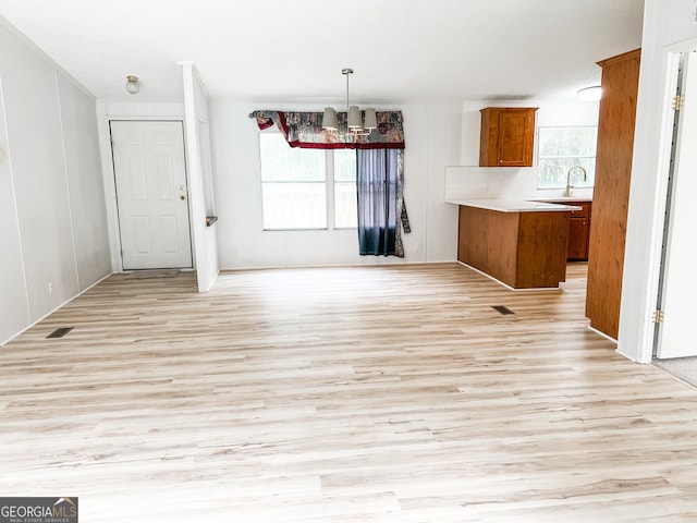 unfurnished dining area featuring an inviting chandelier and light wood-style flooring