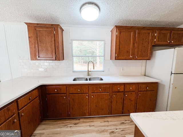 kitchen featuring a sink, a textured ceiling, backsplash, and light countertops
