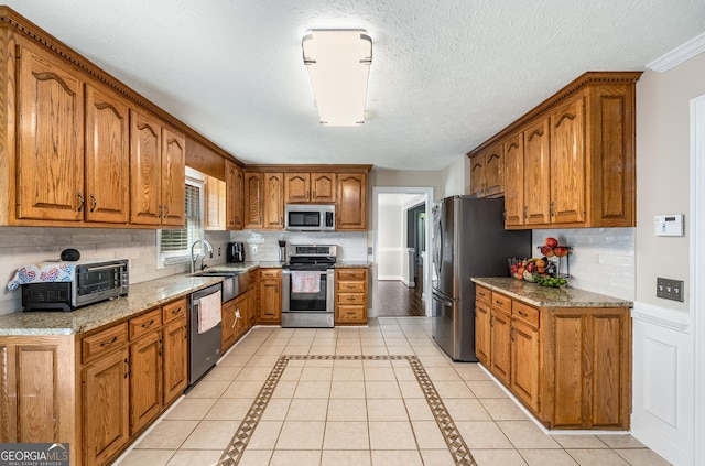 kitchen with stainless steel appliances, brown cabinetry, and a sink