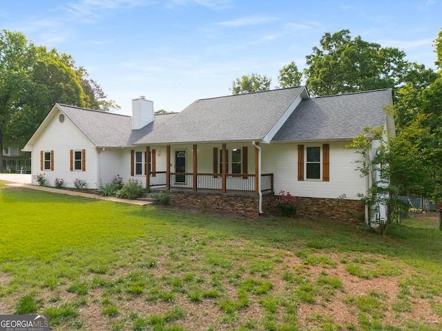 view of front of house with covered porch, roof with shingles, a chimney, and a front yard