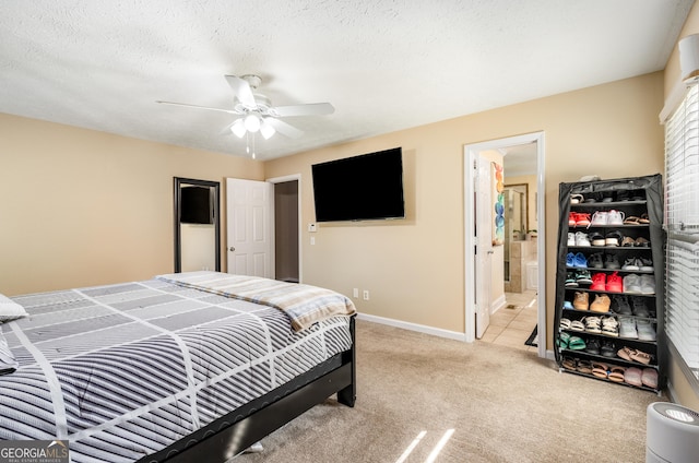 bedroom featuring ensuite bathroom, light carpet, baseboards, and ceiling fan
